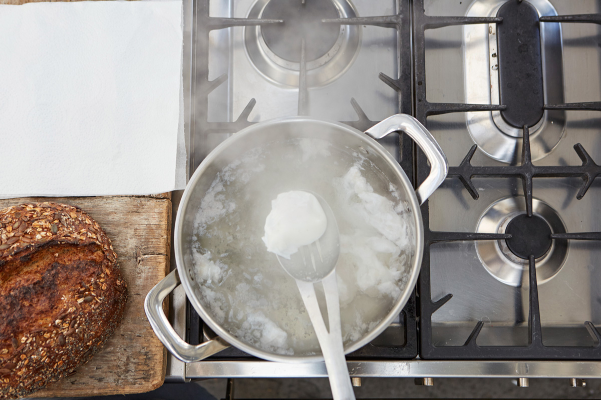Image of a poached egg being removed from the pan of boiling water