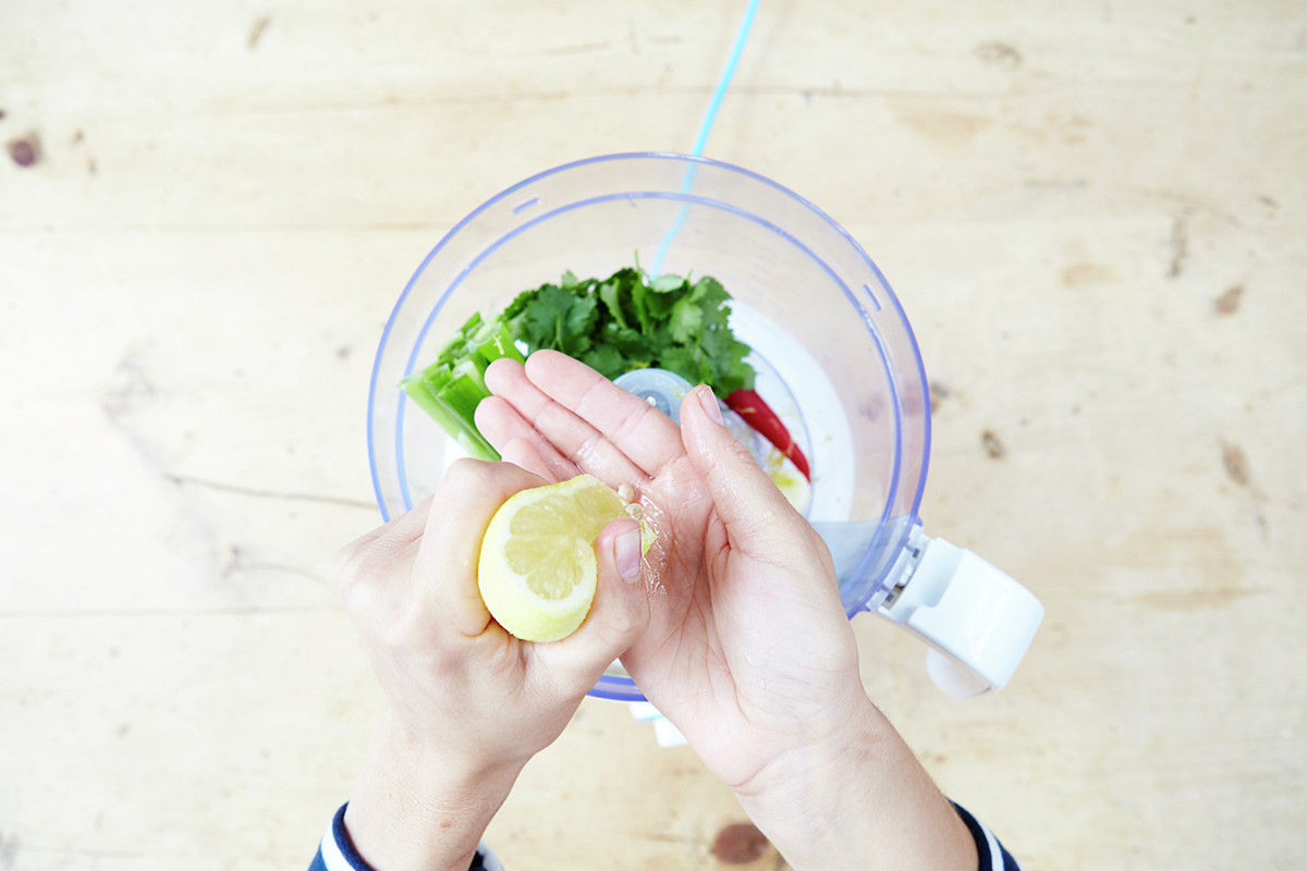 Image of lemon being squeezed into blender with other ingredients