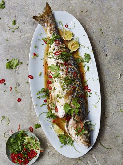 plate of full bass with asian sauce and slices of lemon