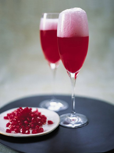 two glasses of champage and pomegranate juice and a plate of pomegranate seeds